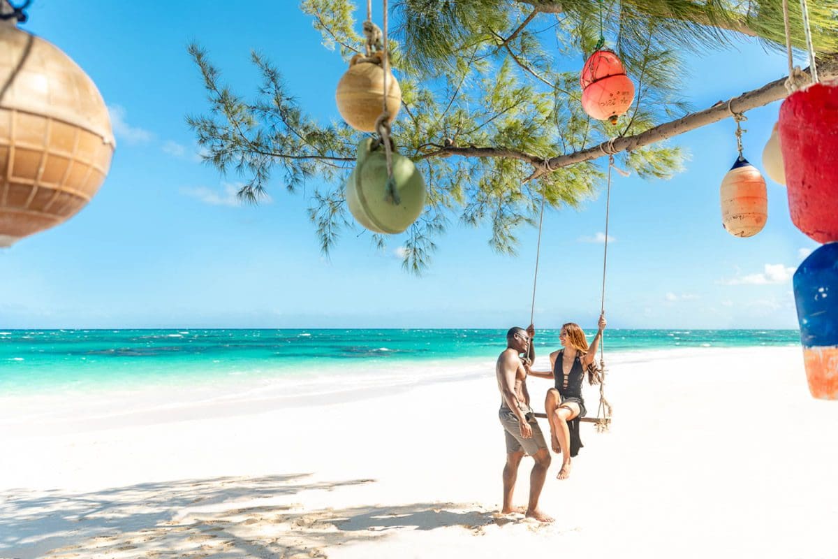 Couple enjoying a beach rope swing - Bahamas Tourism Centre