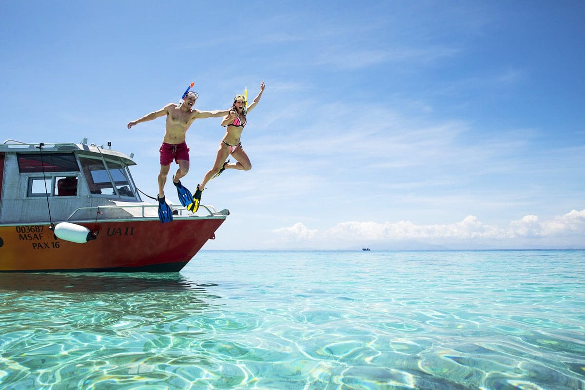 Snorkel couple jumping from a boat in Mamanucas - Tourism Fiji