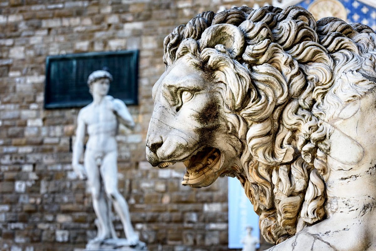 Statue of lion at Loggia Dei Lanzi in front of Florence Palazzo Vecchio and statue of David in Florence, Italy