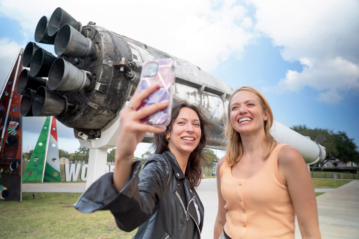 Visitors taking a selfie with the SpaceX Falcon 9 booster on display at Space Center Houston - Brand USA