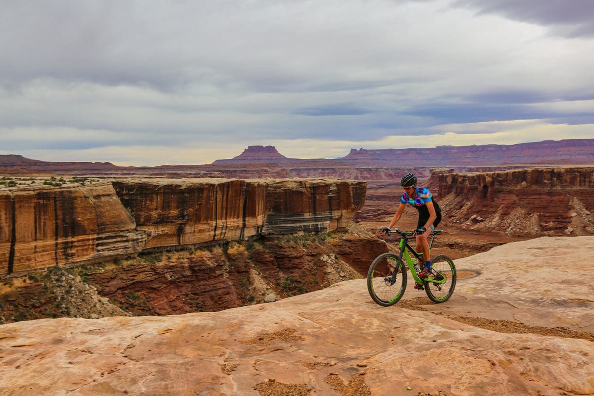 Cycling by on the the canyon cliffs of Canyonlands National Park, Utah