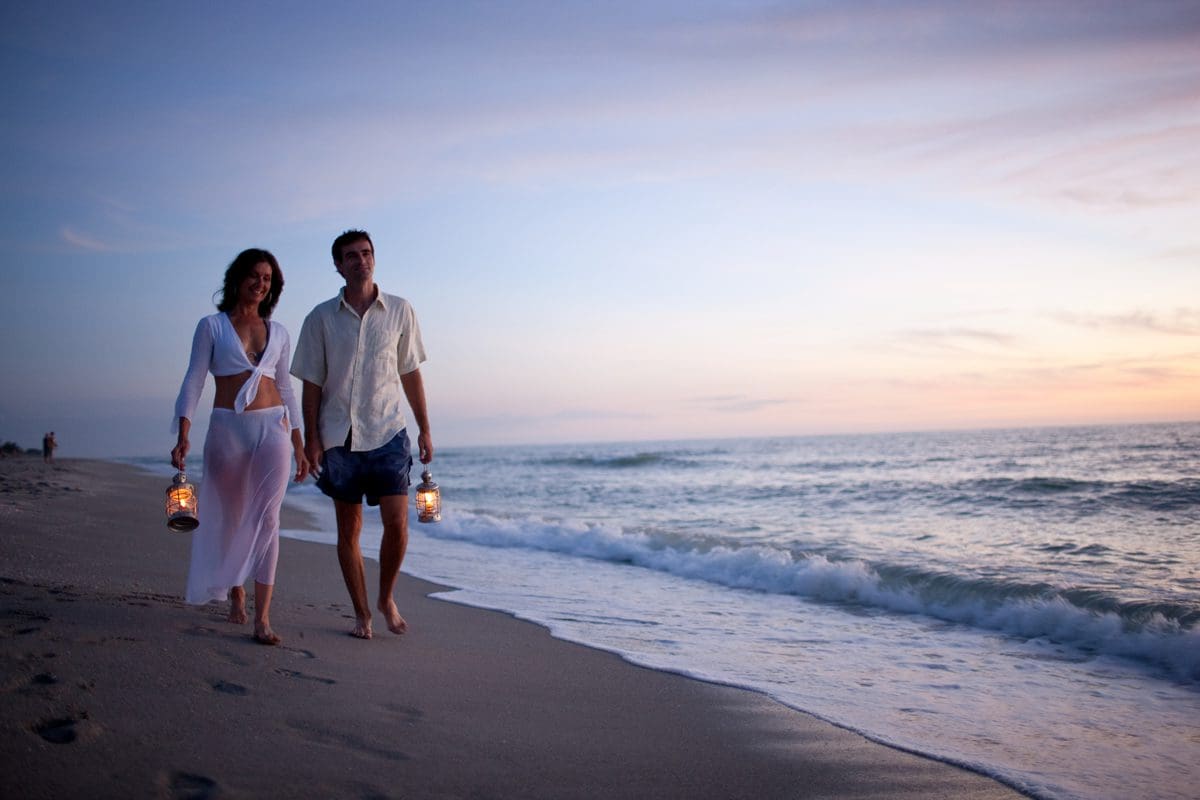 Couple stroll along the beach after sunset - Lee County Visitor Convention Bureau/Jason Lindsey