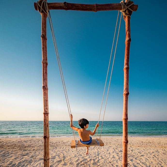Child enjoying a beach swing - Ajman Tourism