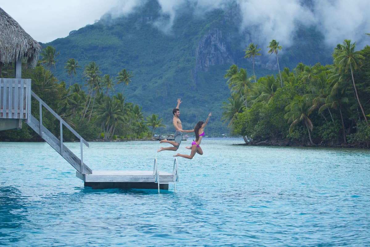 Couple jumping into the waters of Bora Bora - Tahiti Tourisme