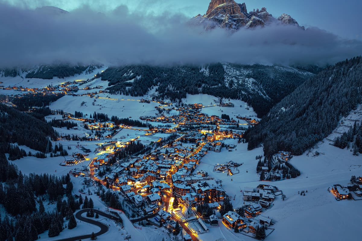 Aerial drone view of the Corvara village covered in snow, in South Tyrol, the Dolomites, in northern Italy in the evening